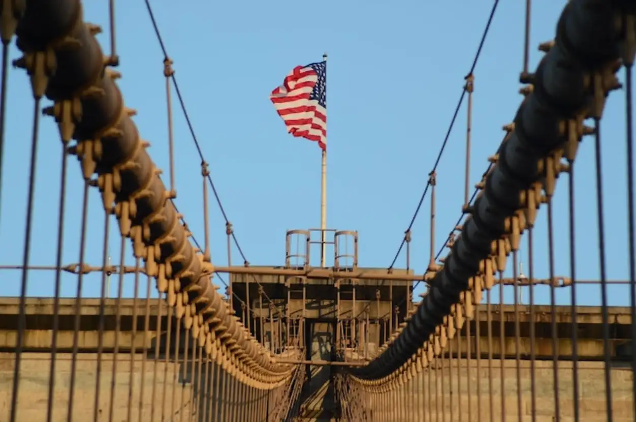 The united states flag on top of brooklyn bridge