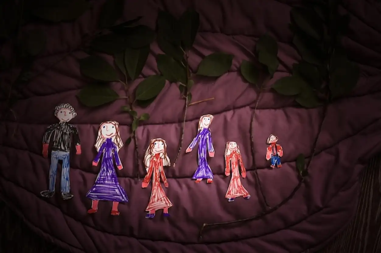 Carved figurines of family painted by child dark fabric background happy childhood creativity