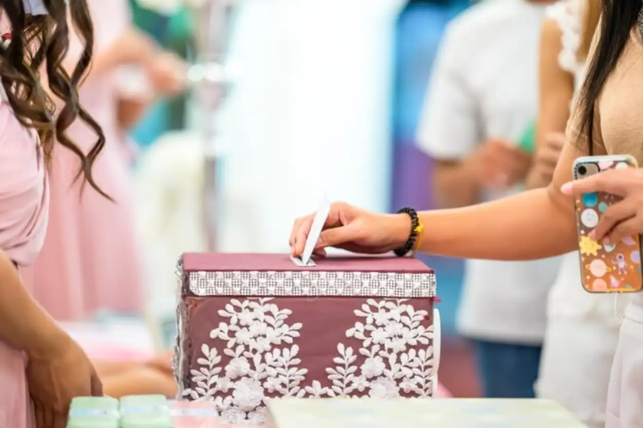 Hand puts an envelope with money into a wedding festive box for gifts to the newlyweds