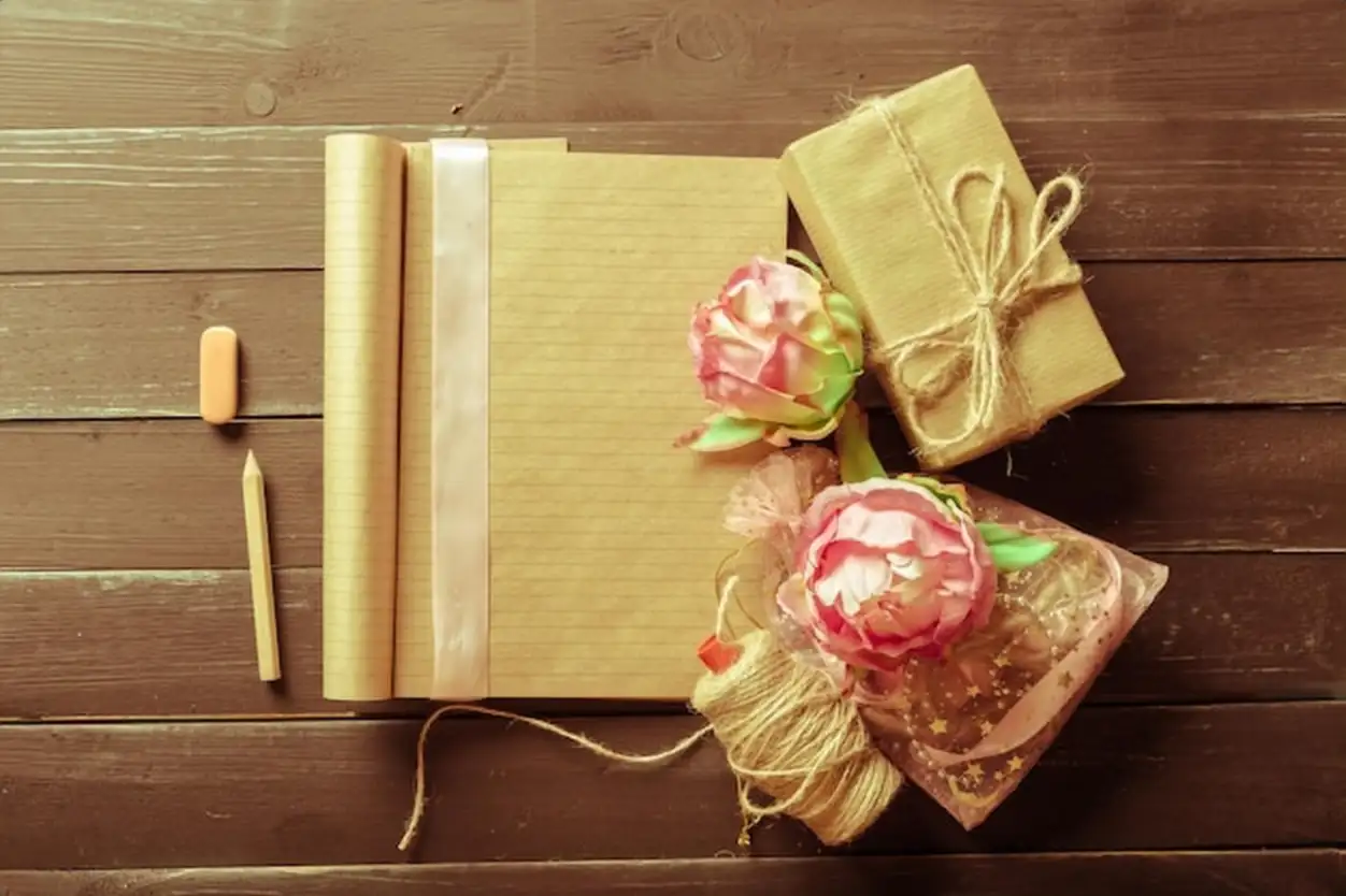 Flowers and a notebook on wooden background