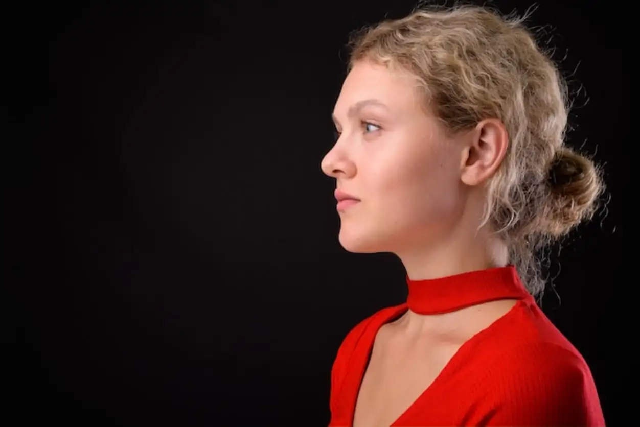 Young beautiful woman with blond curly hair against gray