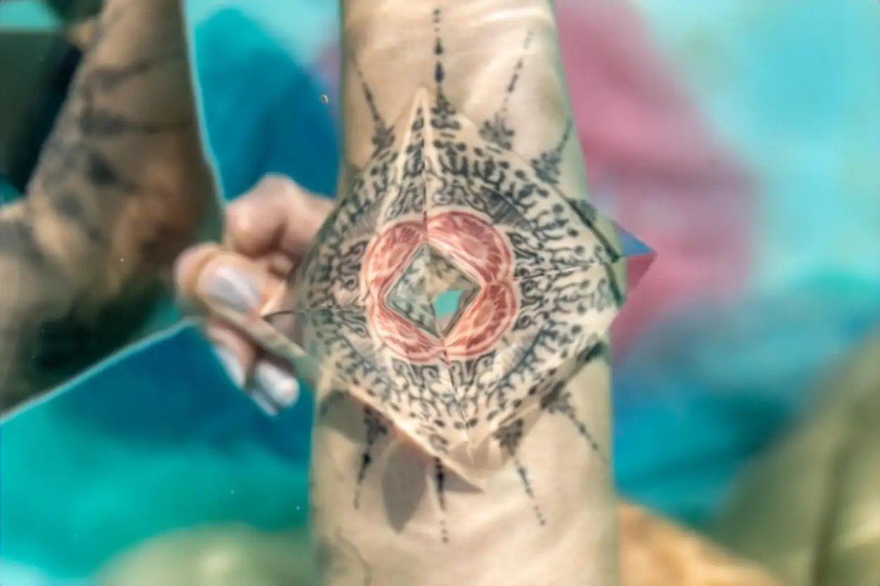 Cropped image of woman with prism on tattoo underwater