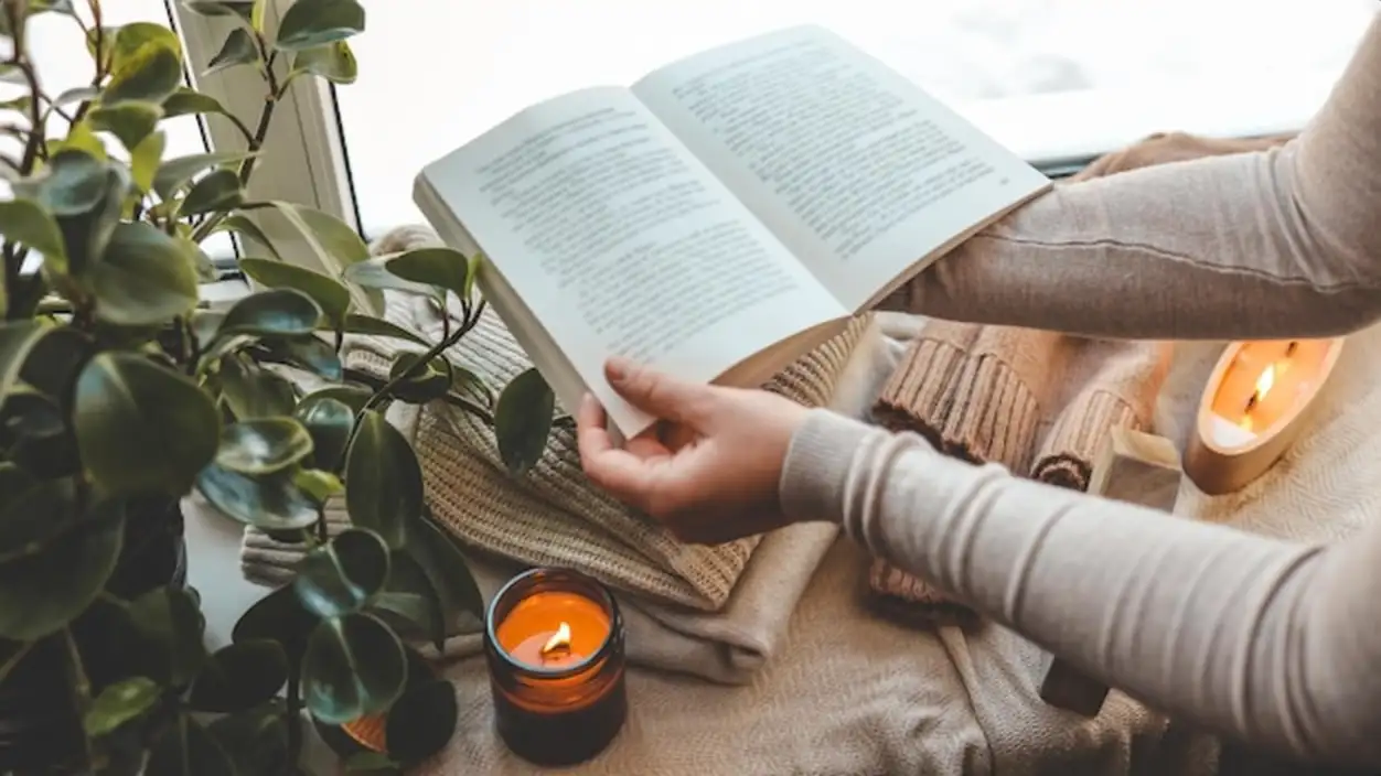 Girl holding a book in her hands cozy morning