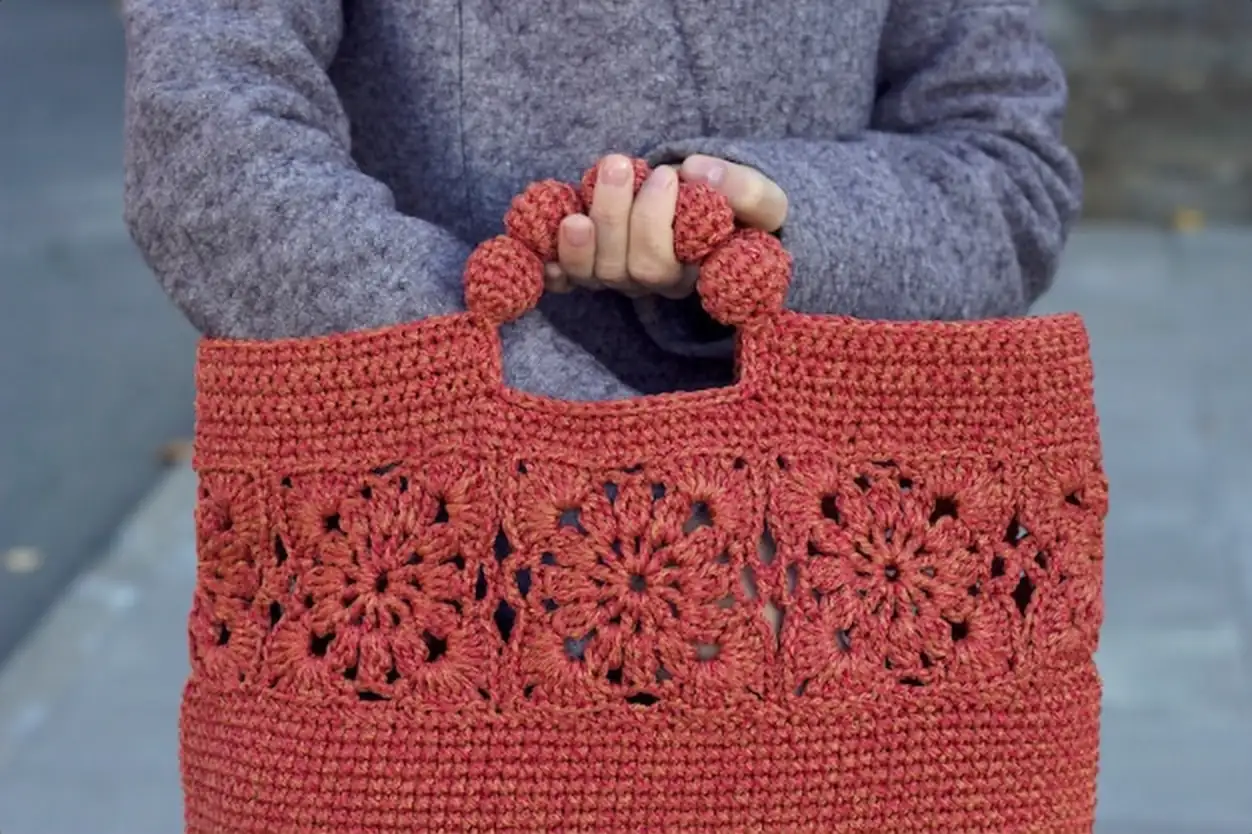 Hands holding a red knitted bag Warm clothes and accessories for cold season Seasonal shopping