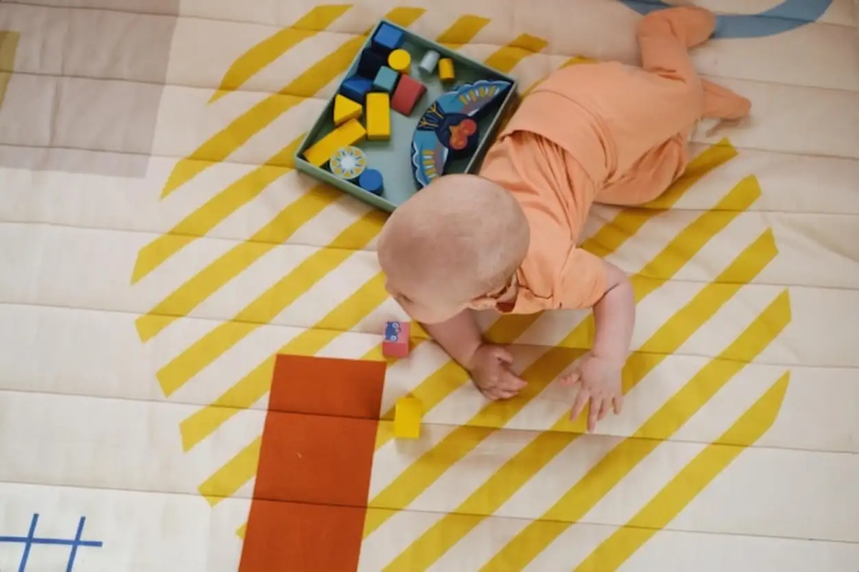 Baby on the floor of kids play room learning to crawl