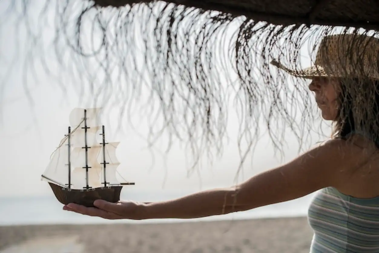 Woman holding toy boat at beach