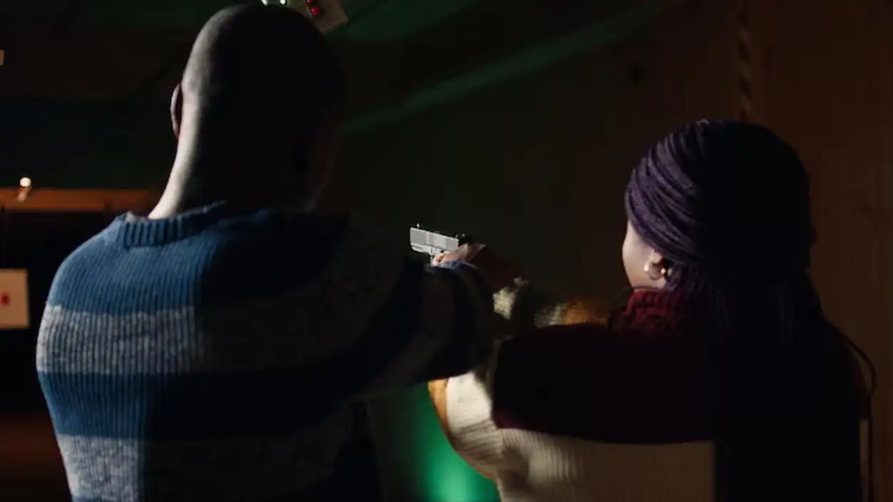 Shooting gallery worker teaching student how to hold pistol close up