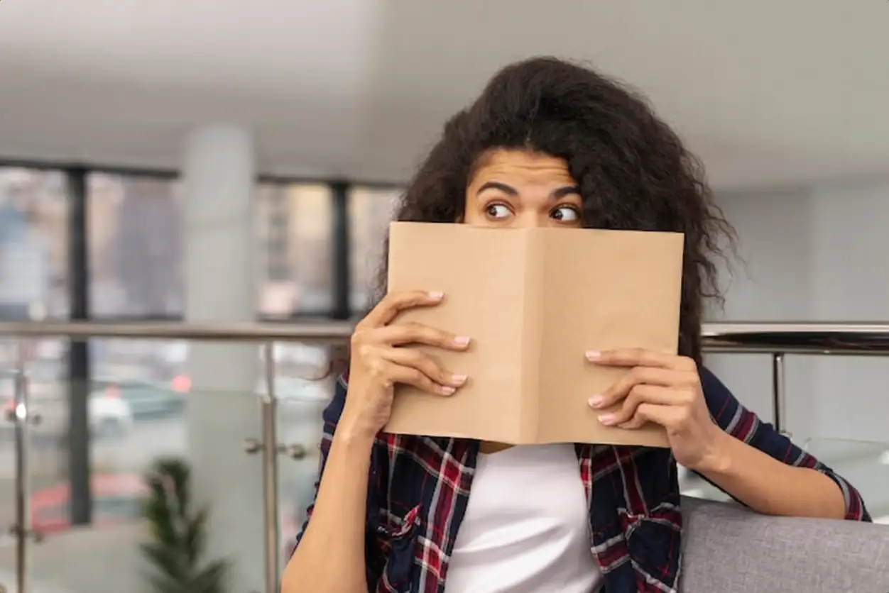 Front view girl covering her face with book