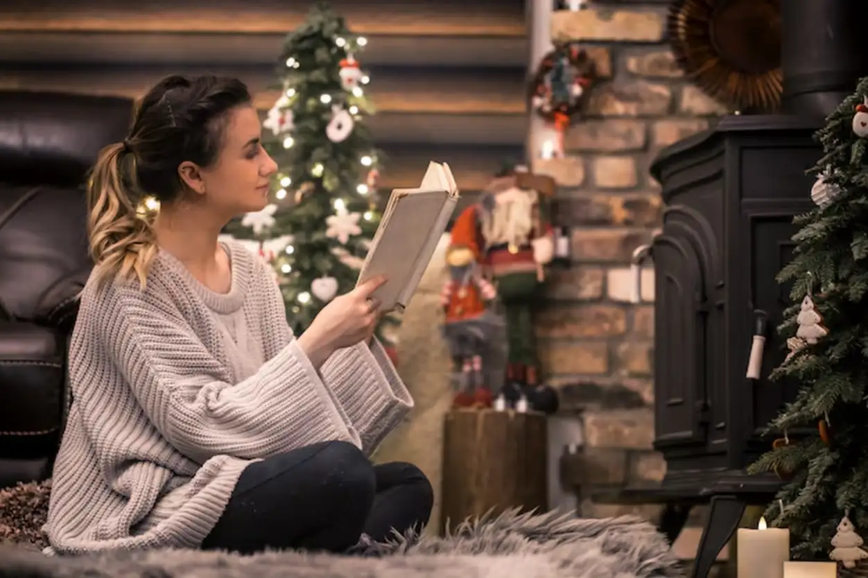 girl reading a book in a cozy home atmosphere near the fireplace